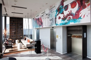 Un moderno vestíbulo de hotel con un largo mostrador de recepción, una zona de estar y un mural en la pared.