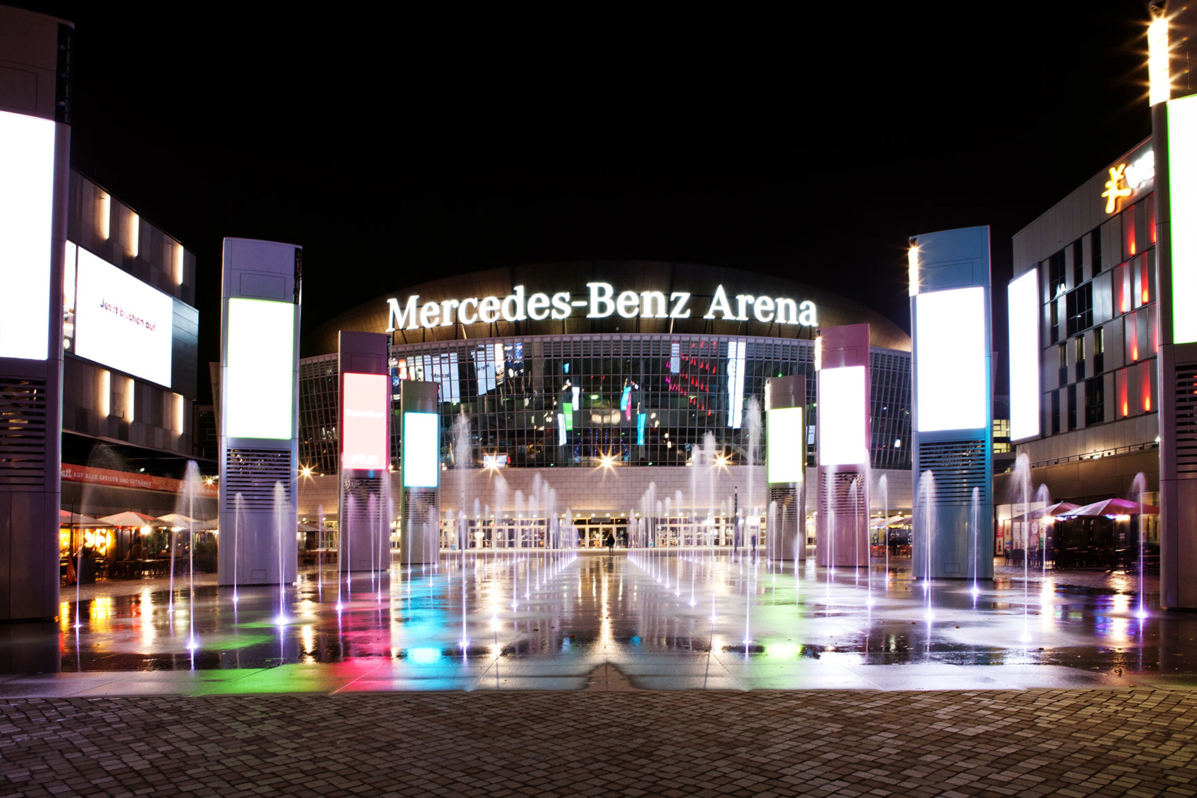 La Arena Mercedes-Benz con un espectáculo de fuente de agua central.