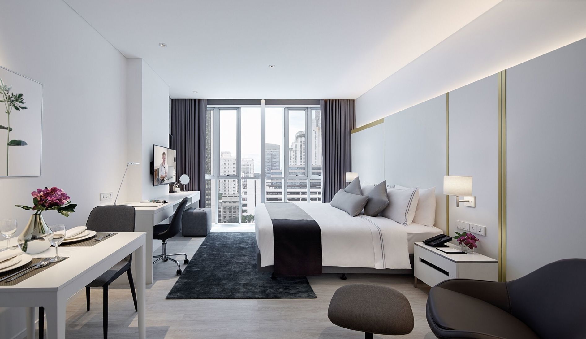 Ein modernes Hotelzimmer mit Bett, Schreibtisch, Stuhl und Blick auf die Stadt.