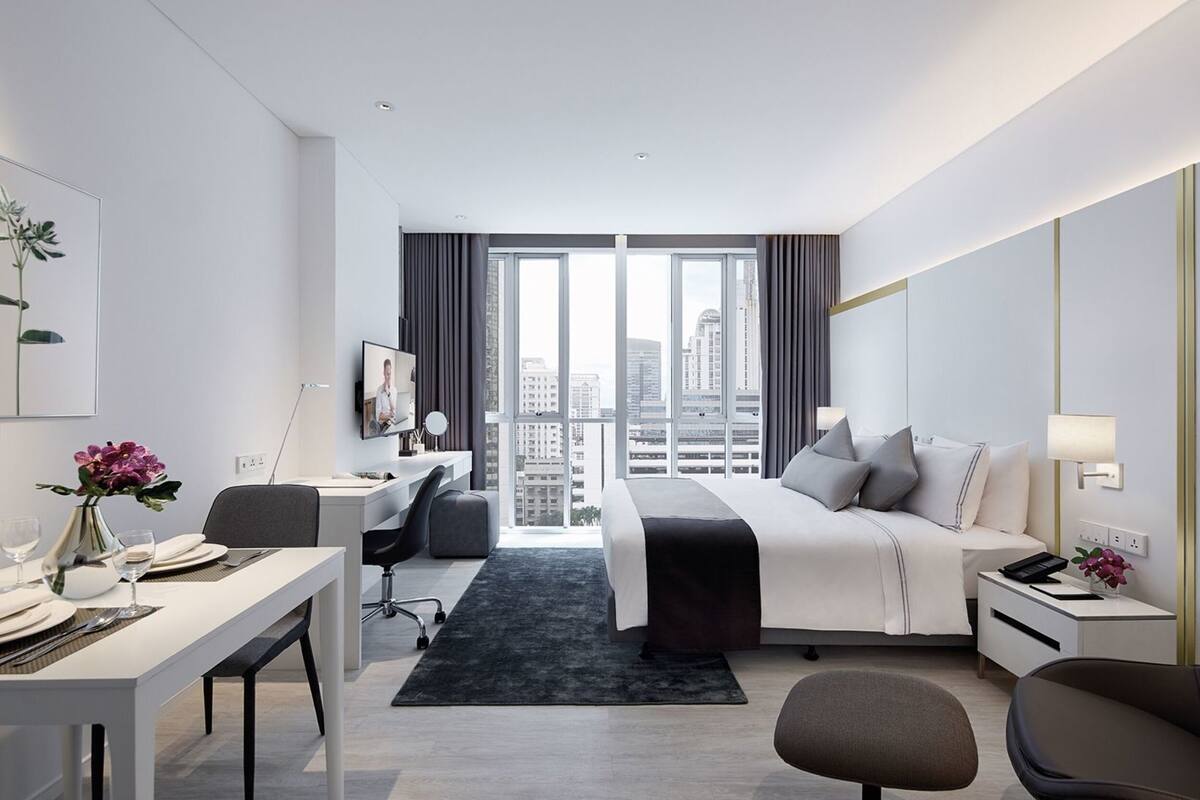 Ein modernes Hotelzimmer mit Bett, Schreibtisch, Stuhl und Blick auf die Stadt.