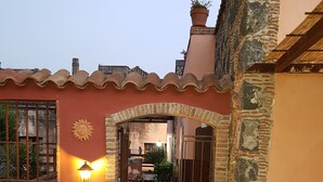 Um pátio com piso de azulejos, portão de ferro forjado e um vaso com planta.