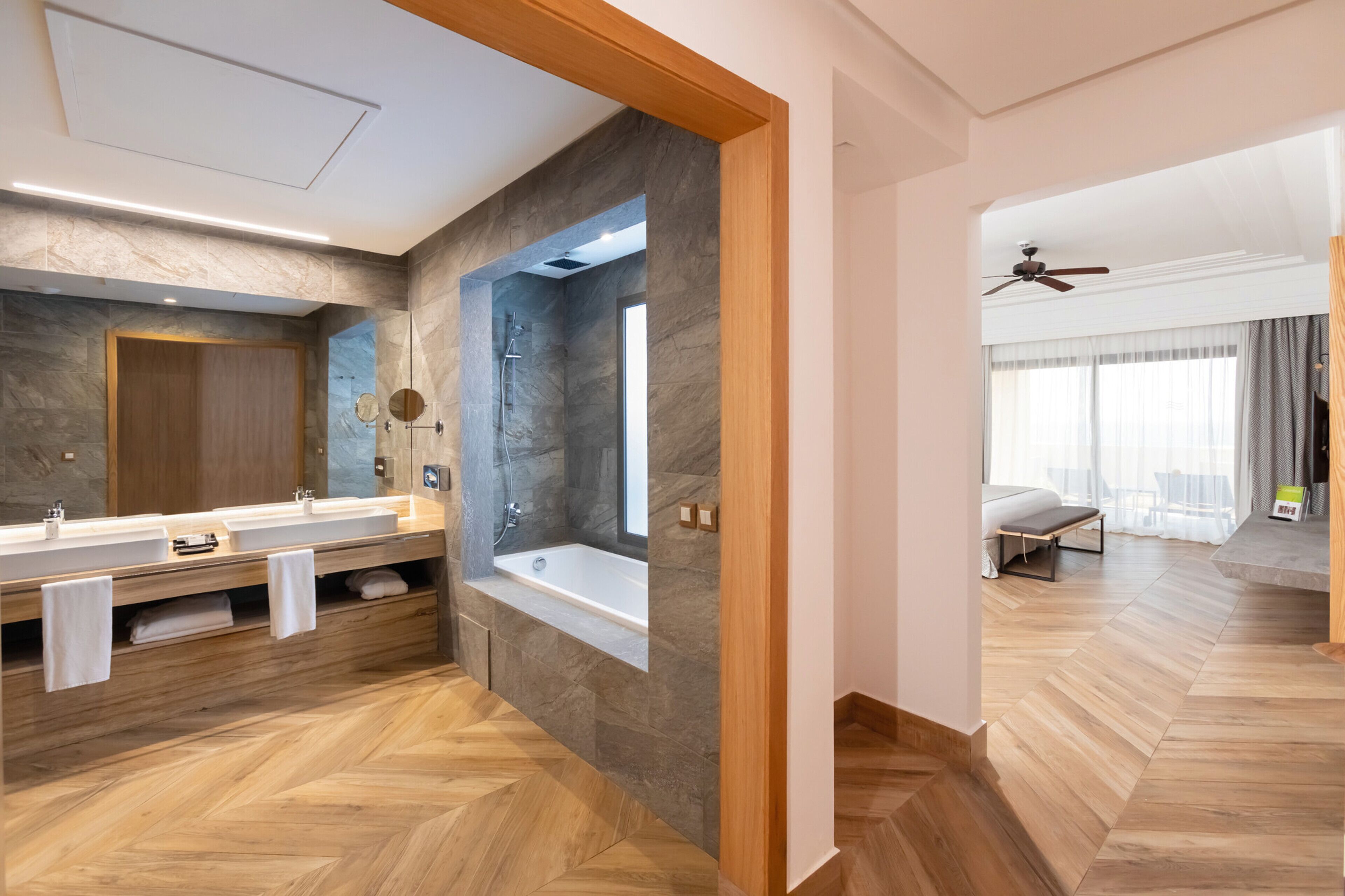 A modern bathroom with a large mirror, dual sinks, and a bathtub.