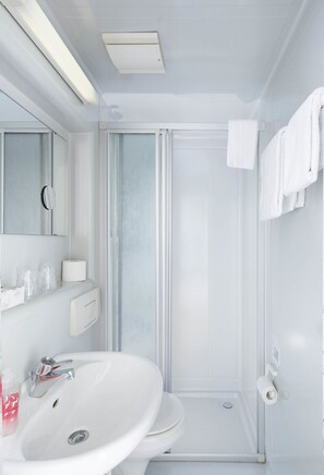 Un baño moderno con lavamanos, inodoro y ducha blancos.