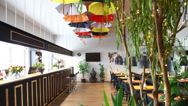 A modern restaurant with a wooden floor, a counter with a cash register, and multiple tables and chairs. - Hotel Moerser Hof (Moers)