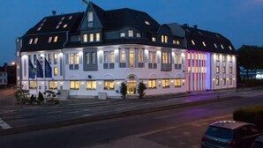 A large, historic hotel with multiple stories, a prominent entrance, and a well-lit facade. - Hotel Moerser Hof (Moers)