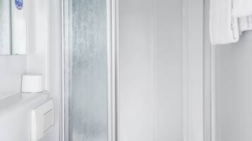 Et moderne badeværelse med en hvid vask, et spejl, et håndklædestativ og en brusekabine i glas.