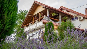 A rustic chalet with a stone facade, wooden balconies, and hanging flower baskets.