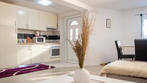 A modern kitchen with white cabinets, a microwave, and a dining area with a table and chairs.