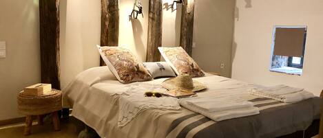 A bedroom with a large bed, wooden beams, and wall-mounted lights.