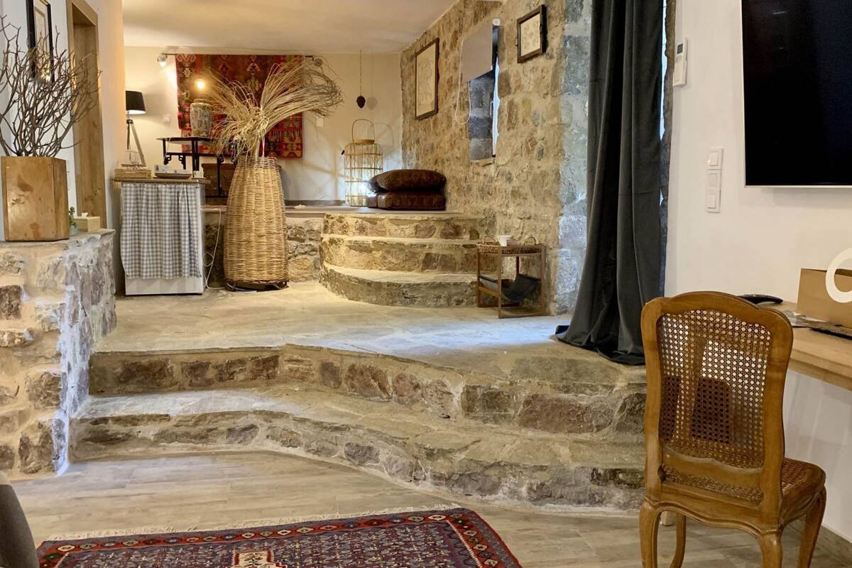 A stone staircase leading to a living area with a television, a wooden chair, and a patterned rug.