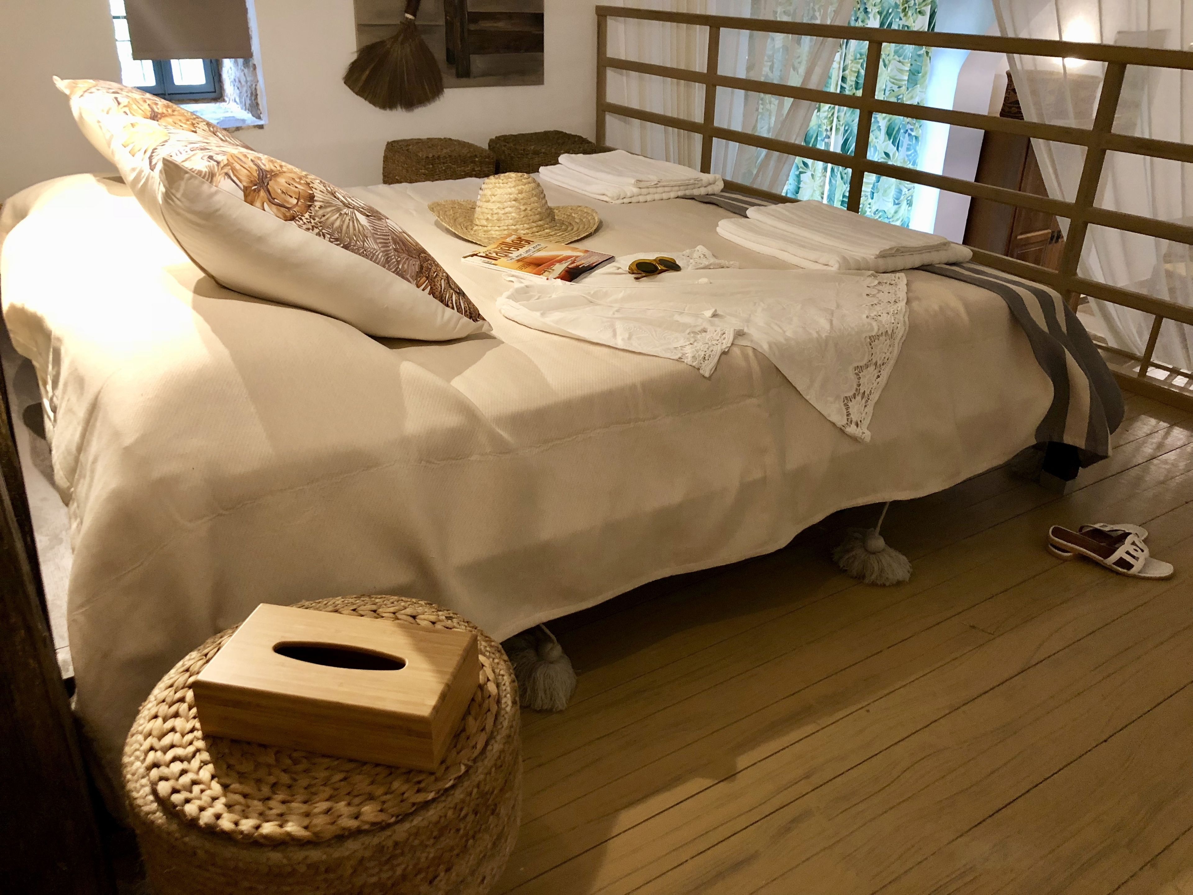 A neatly made bed with a white bedspread, a wooden headboard, and a woven basket on the floor.