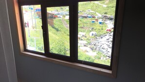 A window with a view of a rural landscape, including a road, houses, and greenery. - Yedigoller Hotel & Restaurant (Çaykara)
