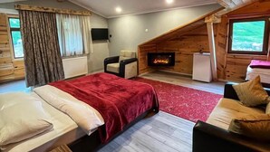 A cozy room with a bed, a sofa, a fireplace, and a television. - Yedigoller Hotel & Restaurant (Çaykara)