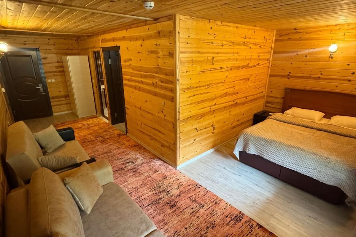 A log cabin room with a bed, a sofa, and a door.