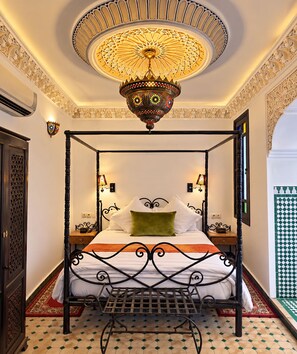 Ein Bett mit Baldachin, eine dekorative Deckenleuchte, ein gemusterter Boden und eine Wandlampe.