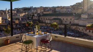Terrassa amb taula per a dues persones, amb vista a un paisatge urbà ple d'edificis històrics i una torre.