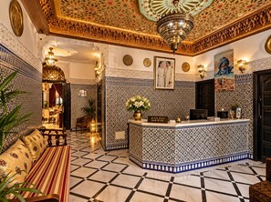 A lobby with a reception desk, patterned walls, and a chandelier. - Riad Fes Bab Rcif & Spa (Fes)