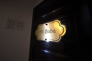 Un letrero con el nombre 'Ali Baba' en una puerta de madera oscura.