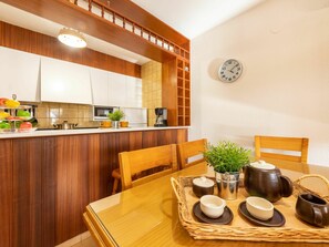 A modern kitchen with wooden cabinets, a built-in microwave, and a clock on the wall.