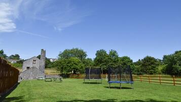 Enjoy a serene outdoor setting with a lawn, playground equipment, and a historic stone building.