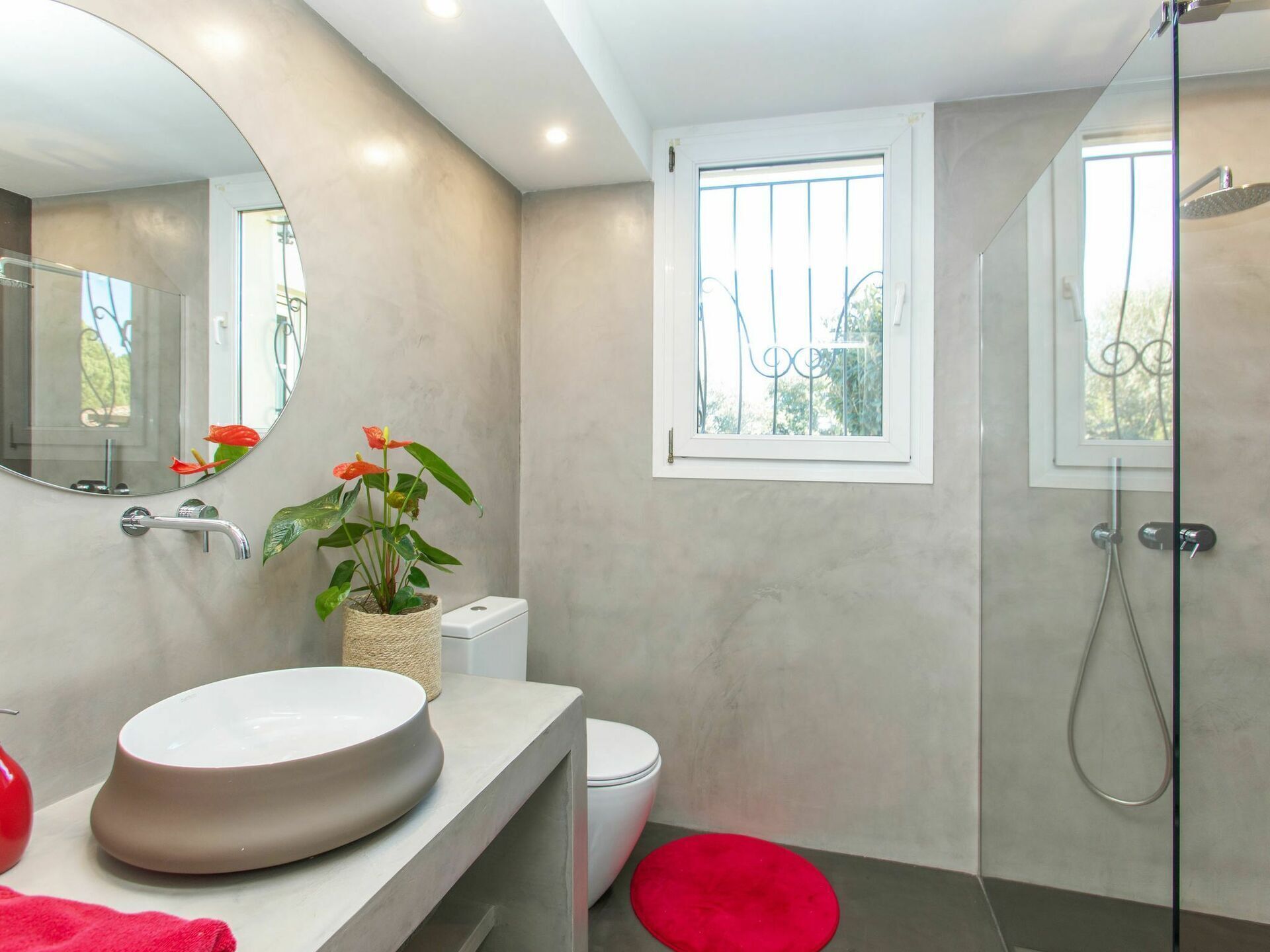 A modern bathroom with a round sink, toilet, and shower.