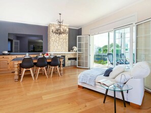 A modern living room with a sofa, a glass coffee table, and a dining area with a table and chairs.