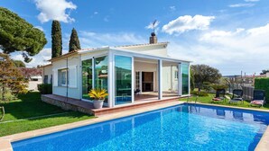 Une maison moderne dotée d’une piscine, de grandes baies vitrées et d’un espace patio.