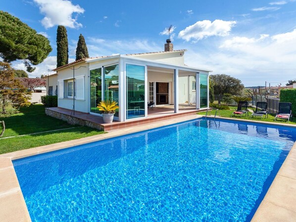 Een modern huis met een zwembad, grote glasramen en een terras.