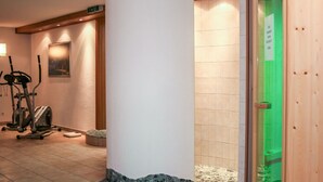 A spa area with a large white pillar, exercise equipment, and a sauna.