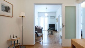 Un salon moderne avec un canapé, une table basse et un téléviseur. On y trouve également un lampadaire et un cadre photo accroché au mur.