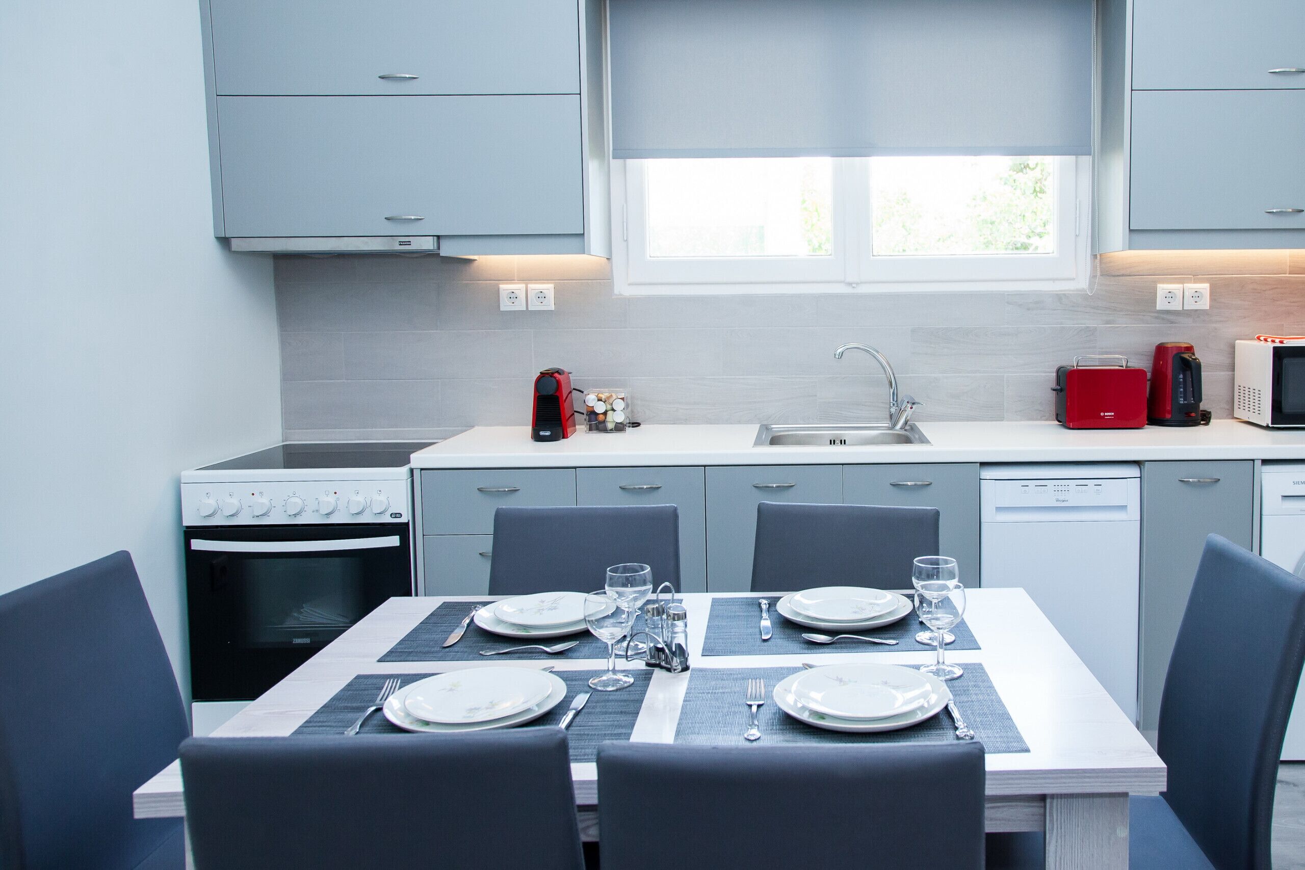 A modern kitchen with grey cabinets, a built-in oven, a microwave, and a sink.