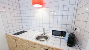 Una cuina americana petita amb un rentaplat, microones i un calefactor portàtil.
