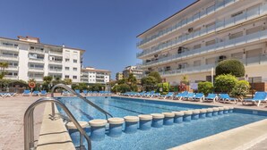 A swimming pool with blue lounge chairs and a metal ladder.