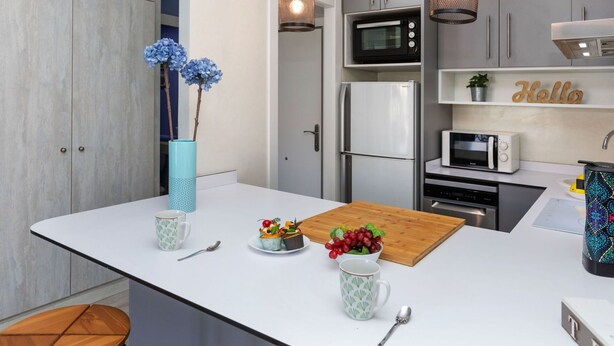 A modern kitchen with a central island, white cabinetry, and stainless steel appliances.