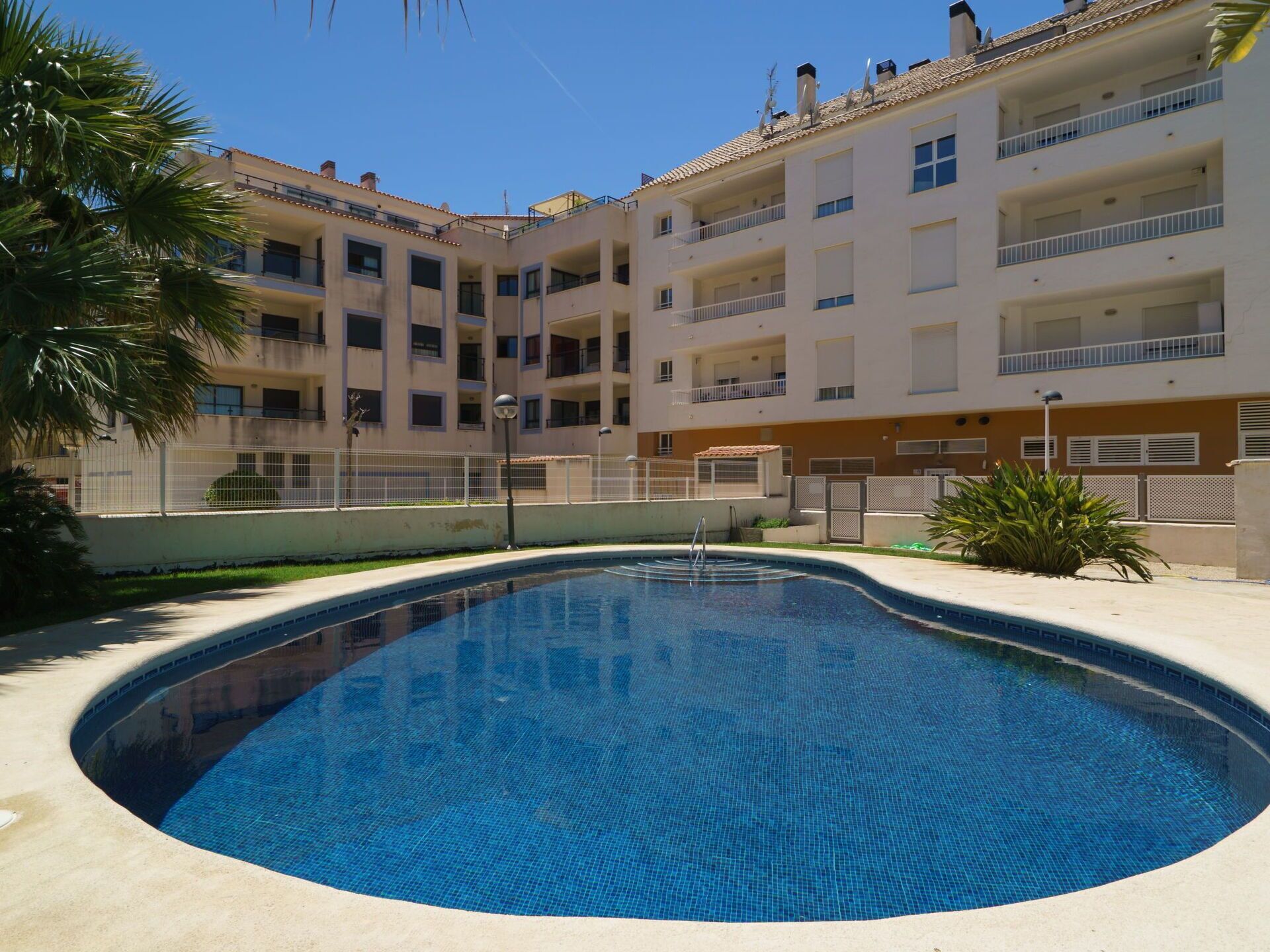 A swimming pool surrounded by a multi-story building with balconies.