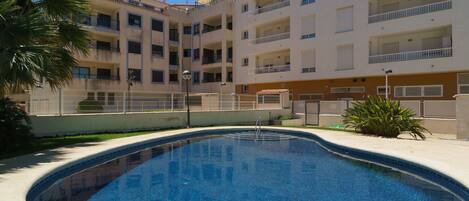 A swimming pool surrounded by a multi-story building with balconies.