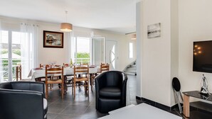 Ein modernes Wohnzimmer mit Essbereich, Fernseher und einer Treppe zu einer weiteren Ebene.