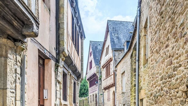 Eine schmale Kopfsteinpflasterstraße, gesäumt von historischen Steinbauten mit Fachwerkhäusern und traditioneller europäischer Architektur.