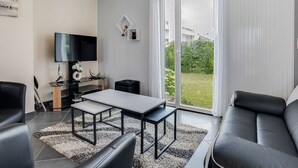 Ein modernes Wohnzimmer mit Flachbildfernseher, Esstisch und Sofa.