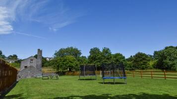 Surrounded by a lush green field and a historic stone building, this serene setting offers a peaceful escape.