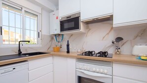 A modern kitchen with white cabinets, a built-in microwave, a stove, and a dishwasher. - Nice apartment for 4 guests with A/C, pool, TV and patio (Calpe)