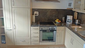 Cocina compacta con estufa, horno y microondas, que cuenta con un protector contra salpicaduras oscuro y armarios claros.