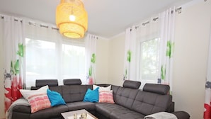 Una sala moderna con un sofá modular, una mesa de centro y una lámpara colgante.