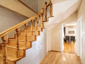 A wooden staircase with a handrail leading to a dining area.