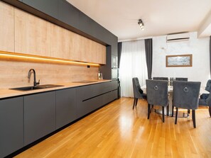 A modern kitchen with a built-in oven, a sink, and a dining area with a table and chairs.