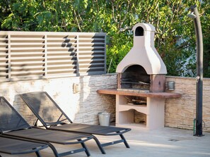 An outdoor seating area with a stone wall and a pizza oven.