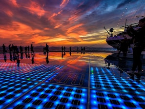 A sunset view from a deck with people walking, a boat, and a reflective floor. - Stunning  villa for 8 guests with WIFI, A/C, private pool, TV, terrace and pets allowed (Zadar)