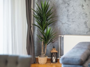 A room with a potted plant, a small table with a lantern, and a blue sofa.