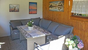 A cozy room with a sofa, a table with a vase of flowers, and wooden walls with framed pictures. - Nice apartment for 4 people with WIFI, TV, patio and pets allowed (Wenns)