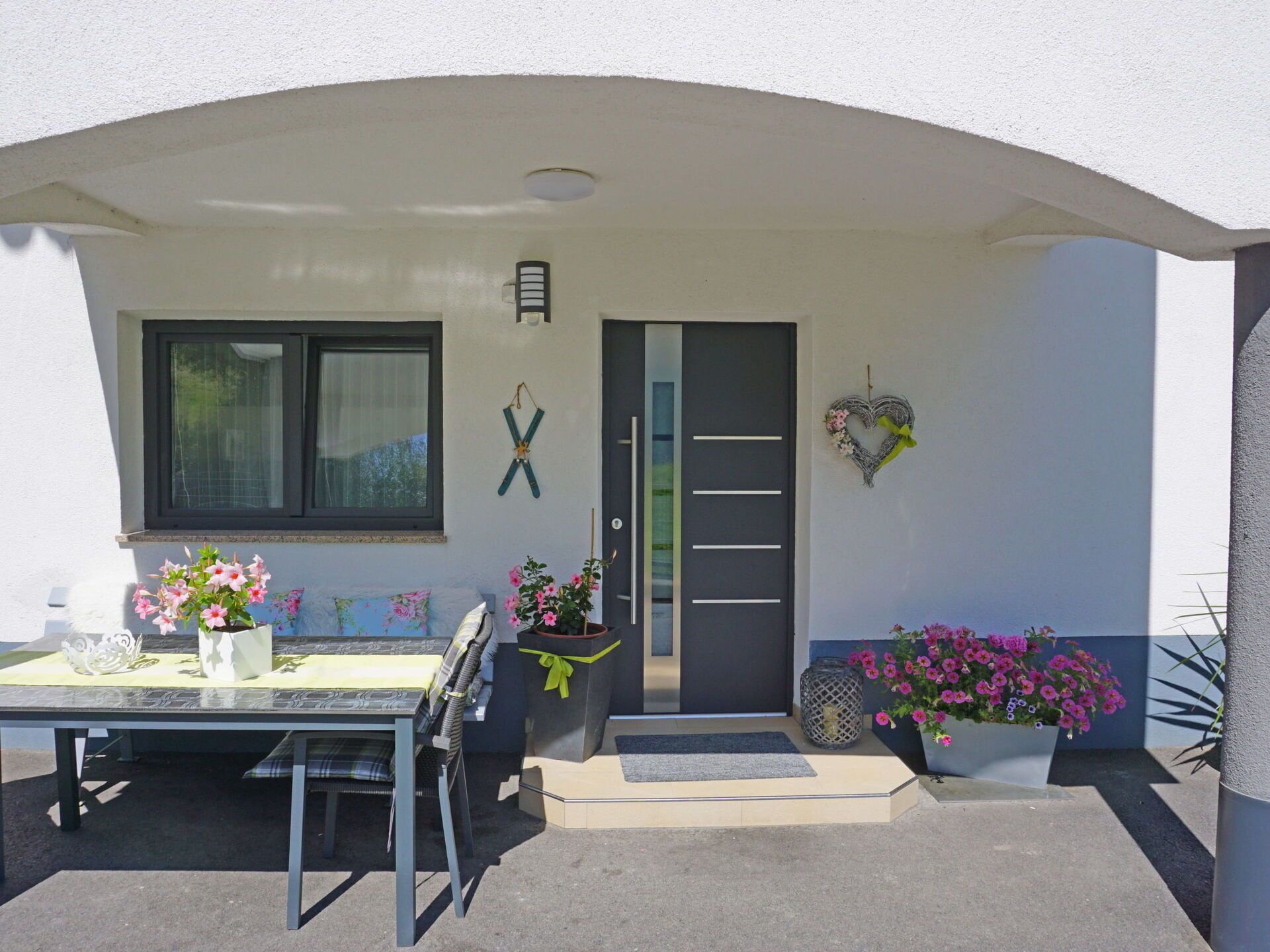 A modern house with a dining area, a black door, and a heart-shaped decoration.